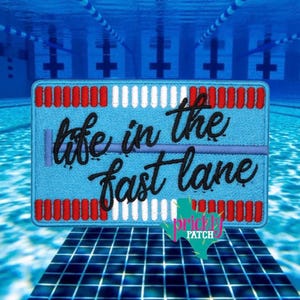 May include: A light blue embroidered patch with the text "life in the fast lane" in black script. The patch has red and white striped borders, and a green and pink logo in the bottom right corner. The background is a swimming pool.