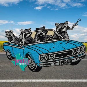 May include: Embroidered patch featuring a blue convertible car with four raccoons. One raccoon is driving, and another is smoking a cigarette. The patch has the word "FERAL" on the license plate and "Prickly Patch" on the bottom left.