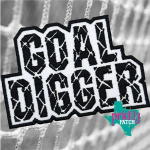 May include: A black and white embroidered patch featuring the text GOAL DIGGER in a bold, blocky font. The letters have a textured, cracked pattern throughout. A small teal logo shaped like the state of Texas with the text prickly PATCH is visible.