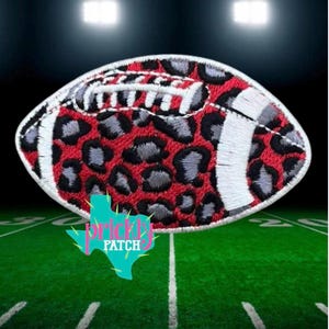 May include: An embroidered patch shaped like an American football, featuring a red and black leopard print pattern with white stitched laces and white stripes on each end. The patch has a white border and includes a teal logo reading Prickly Patch.