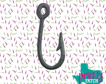 Puede incluir: Un anzuelo de pesca bordado en gris oscuro con un ojal circular. El anzuelo está sobre un fondo blanco con un patrón de guiones rosas y verdes. Un logotipo de Texas turquesa con el texto "prickly PATCH" está en la esquina inferior derecha.
