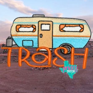 May include: Embroidered patch featuring a vintage camper trailer in beige, blue, and orange. The word "TRASH" is embroidered in large orange letters below the camper. A small cactus logo with the words "Prickly Patch" is on the bottom right.