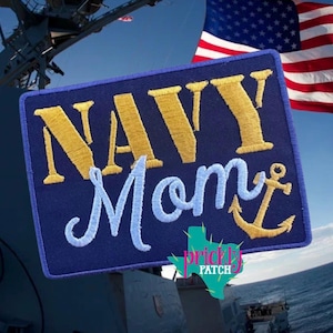May include: A navy blue patch embroidered with the words "NAVY Mom" in gold and light blue thread, featuring a gold anchor. The American flag waves in the background.