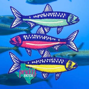 May include: Three embroidered fish patches arranged vertically. The top fish is blue and light green, the middle fish is blue and pink, and the bottom fish is blue and yellow. A green Texas-shaped logo with the text Prickly Patch is visible.