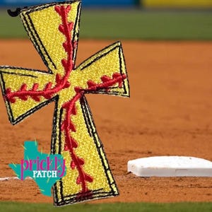 May include: A yellow softball cross-shaped patch with red stitching, outlined in black. The patch is set against a baseball field background, with a white base in the foreground. The patch has the text "prickly patch" in a turquoise Texas-shaped logo.