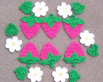 May include: A collection of handmade crochet strawberry and flower appliques. The strawberries are bright pink with green tops, and the flowers are white with yellow centers. Green leaves are also included.