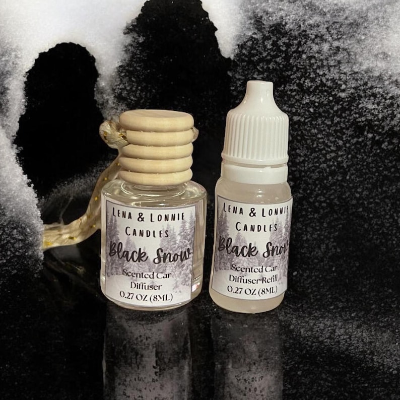 May include: Two small glass bottles of Lena & Lonnie Candles Black Snow scented car diffuser and diffuser refill. The diffuser bottle has a wooden top and a label with the product name and scent. The refill bottle has a white cap and a label with the same information. Both bottles are 0.27 OZ (8ML).