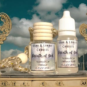 May include: Two small glass bottles with wooden caps and white labels. The labels read "Lena & Lonnie Candles Breath of God Scented Car Diffuser 0.27 oz (8 ml)".