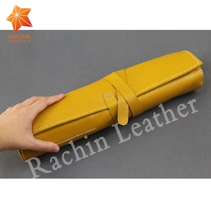 Könnte beinhalten: Eine gelbe Lederrolle mit weißen Nähten und einem Riemenverschluss. Die Rolle ist aufgerollt und trägt den Schriftzug "Rachin Leather".