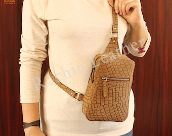 Peut inclure: Un sac à bandoulière en cuir marron avec un motif crocodile. Le sac possède une poche zippée et une bandoulière réglable pour s'adapter à différentes tailles de corps.