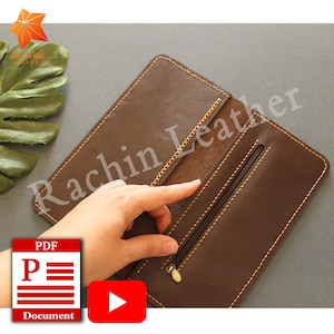 May include: A brown leather wallet with a zippered pocket and a gold zipper pull. The wallet is open and the inside is visible. The wallet is made of high-quality leather and has a stitched edge.