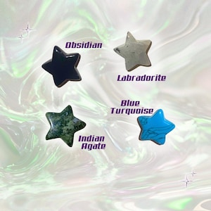 May include: Four star-shaped gemstones: Obsidian (black), Labradorite (gray), Indian Agate (green), and Blue Turquoise. Each stone is labeled with its name in a stylized font. The background has a swirling, iridescent effect.