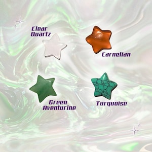 May include: Four star-shaped gemstones: clear quartz, carnelian, green aventurine, and turquoise. Each stone is labeled with its name in a stylized font. The background has a swirling, iridescent effect.