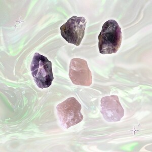 May include: A collection of raw amethyst and rose quartz crystals. The amethyst crystals show various shades of purple, and the rose quartz crystals are a soft pink. The crystals are set against a pearlescent, swirling background with star accents.