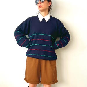 May include: A white ceramic mug with a black handle and the text "But First, Coffee" in a black, bold font. The mug is on a wooden surface. The mug is approximately 10 cm tall.