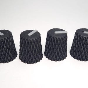 Może przedstawiać: Cztery czarne zamienniki gałek z fakturowaną powierzchnią i białym paskiem na górze.