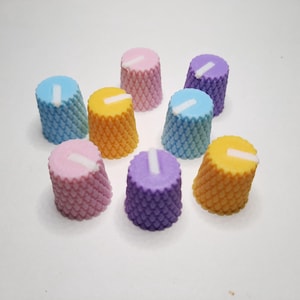 Puede incluir: Surtido de pomos coloridos con una superficie texturizada y una línea blanca en la parte superior. Los pomos son en tonos de azul, amarillo, rosa y morado.