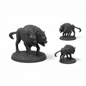 May include: Three dark gray wolf figurines. One is a two-headed wolf, and the other two are single-headed wolves. All are standing on circular bases with a cobblestone pattern. The figurines are likely for tabletop gaming or display.