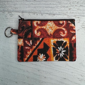May include: A small orange, black, and white patterned zippered pouch with a key ring attached.