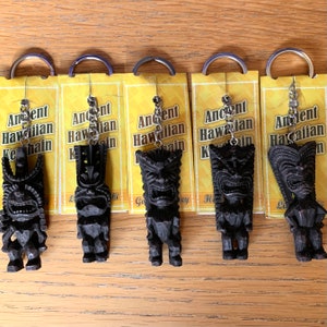 May include: Five black wooden tiki keychain charms with silver key rings and yellow card tags that read "Ancient Hawaiian Keychain".