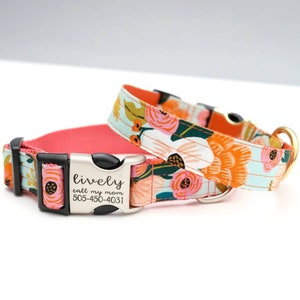 May include: Two floral dog collars. One collar is light blue with orange, pink, and white flowers. The other collar is coral pink. The metal buckle on one collar reads "lively call my mom 505-450-4031".