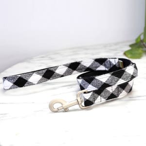 May include: Black and white buffalo plaid dog leash with a silver clip.