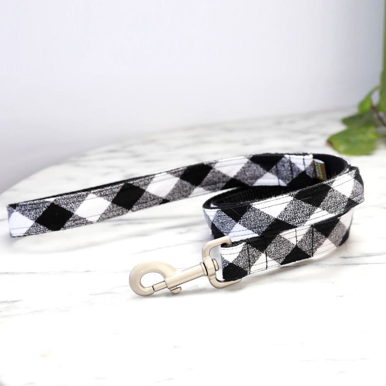 May include: Black and white buffalo plaid dog leash with a silver clip.