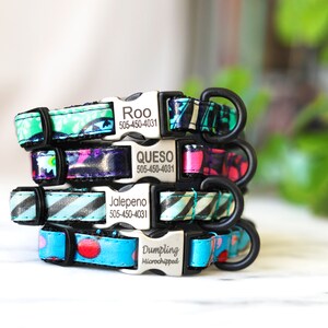 May include: A stack of personalized dog collars with various colorful patterns. Each collar features a metal buckle with a name and phone number engraved on it. The collars are in shades of blue, green, purple, and pink, with floral and geometric designs.