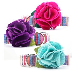 Puede incluir: Tres collares para perros con tela a rayas de colores y detalles de flores de fieltro. Las flores son rosas, moradas y turquesa.