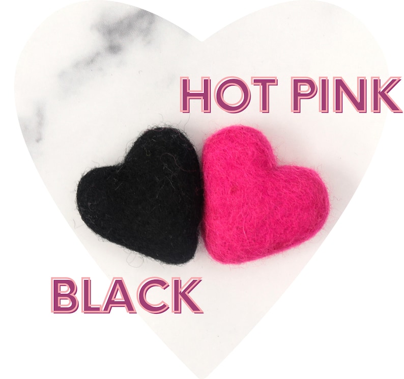 May include: Two felt hearts, one black and one hot pink, on a white marble background. The text "HOT PINK" is above the pink heart and the text "BLACK" is below the black heart.