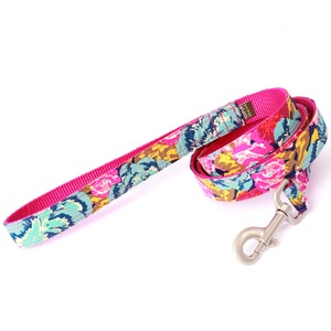 May include: A pink dog leash with a floral print and a silver clip. The leash is made of a durable nylon material and is perfect for walking your dog.