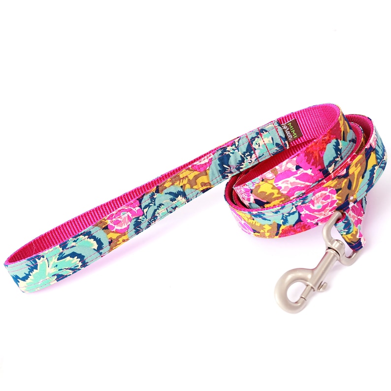 May include: A pink dog leash with a floral print and a silver clip. The leash is made of a durable nylon material and is perfect for walking your dog.