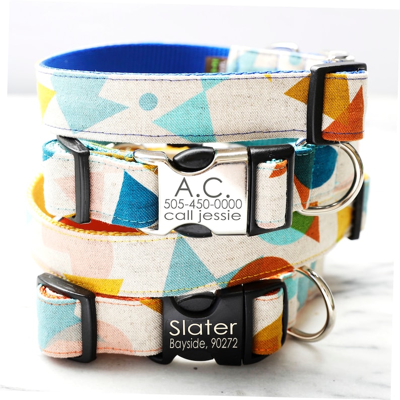 Op de afbeelding: Drie hondenhalsbanden met geometrische patronen in tinten blauw, oranje, geel en roze. De halsbanden hebben zwarte gespen en zilveren naamplaatjes met de tekst "A.C. 505-450-0000 call jessie" en "Slater Bayside, 90272".
