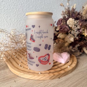 May include: Frosted glass tumbler with a bamboo lid, decorated with hearts, stars, and hockey-themed illustrations. Text includes "I might knock, I might open" and "I need... You". The tumbler sits on a wooden tray.