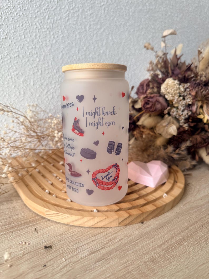May include: Frosted glass tumbler with a bamboo lid, decorated with hearts, stars, and hockey-themed illustrations. Text includes "I might knock, I might open" and "I need... You". The tumbler sits on a wooden tray.