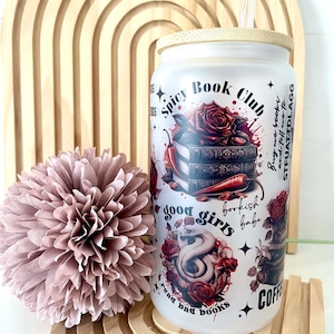 Könnte beinhalten: Ein Glasbecher mit Bambusdeckel und Strohhalm. Der Becher hat ein Design mit Rosen, Chilischoten, Büchern und dem Text "Spicy Book Club", "good girls read bad books" und "Buy me books and tell me to STFUATDLAGG".