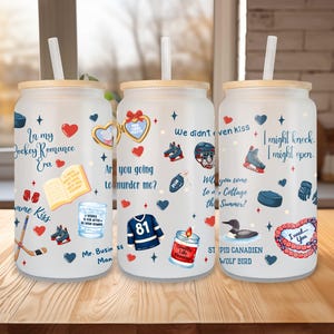May include: Three glass tumblers with wooden lids and straws, decorated with hockey-themed graphics and text. Designs include hearts, hockey equipment, and phrases like "In my Hockey Romance Era" and "I need you."