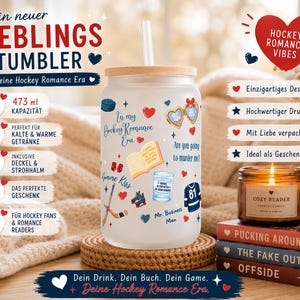 May include: A frosted glass tumbler with a wooden lid and straw, featuring hockey-themed graphics and text. The tumbler has a capacity of 473 ml and includes the text "In my Hockey Romance Era". A candle and books are in the background.