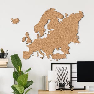 Peut inclure: Une carte en liège marron de l'Europe, comprenant les îles britanniques et l'Islande, fixée sur un mur blanc. La carte est un élément décoratif pour une maison ou un bureau. La carte est en liège.