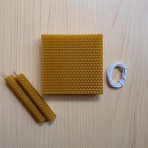 May include: A set of beeswax candle making supplies including a sheet of honeycomb wax, three beeswax candle wicks, and a spool of white twine.