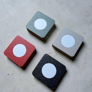 May include: Four square wall-mounted light fittings with a textured finish. Each unit features a central circular white light panel. The set includes one red, one black, one sage green, and one beige fitting, all arranged in a diamond formation.
