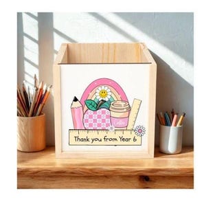 May include: A wooden desk tidy with a colourful design. It features a pink pencil, apple, coffee cup, and rainbow. The text "Thank you from Year 6" is on a ruler. Suitable for school or office stationery.