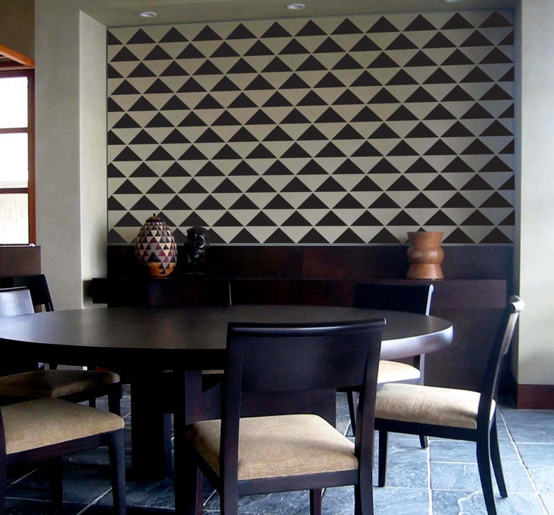 May include: A dining room featuring a dark wood table and chairs. The chairs have tan upholstered seats. The wall is decorated with a repeating pattern of black triangles against a cream background. Decorative vases are on a dark wood shelf.