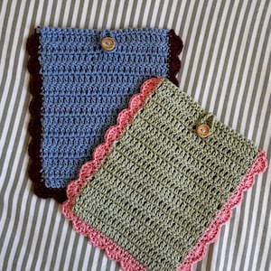 May include: Two rectangular crochet pouches with button closures. One pouch is light blue with a dark brown scalloped border, and the other is sage green with a light pink scalloped border. Both feature a single wooden button at the top centre.