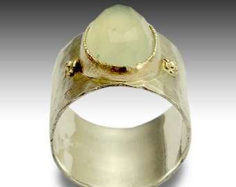 May include: A silver ring with a hammered finish and a light green gemstone set in a gold bezel. The ring has small gold accents on the sides.