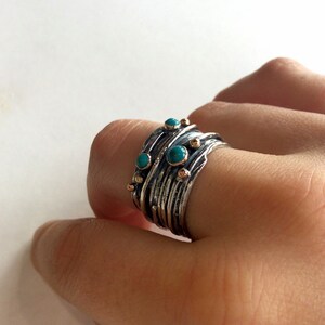 May include: A silver and gold ring with turquoise stones set in a textured band.