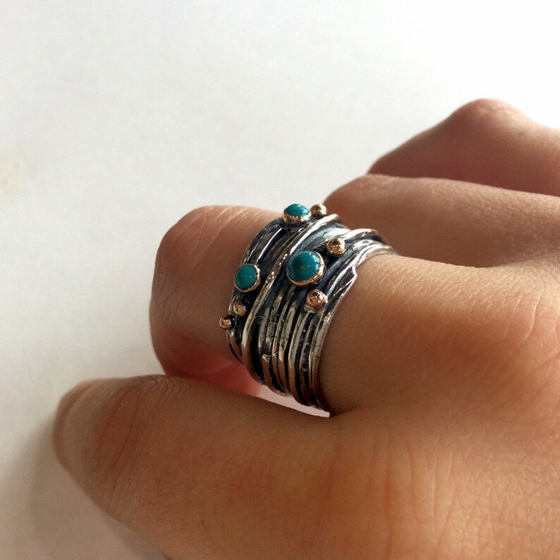 May include: A silver and gold ring with turquoise stones set in a textured band.