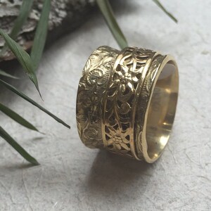 May include: A gold-toned spinning ring with a floral design. The ring is made of multiple bands that spin independently.