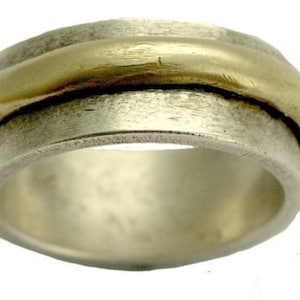 May include: A silver and gold spinning ring with a textured finish. The ring is made of two bands, one silver and one gold, that are joined together.