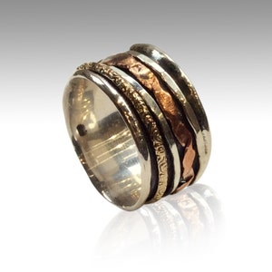 May include: A silver ring with multiple bands of copper, silver, and gold. The bands are textured and have a hammered finish.